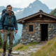 Hiker masculin devant un refuge de montagne en été